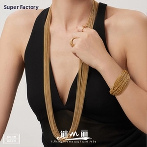 Close-up of a wide multi-strand golden cuff bracelet on a model wearing black clothing