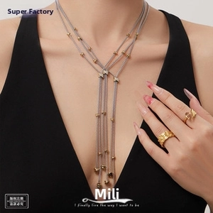 Close-up of layered gold tassel necklace with zircon clasp and gold beads on a model