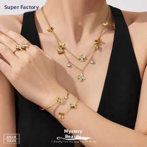 Close-up of golden four-leaf flower jewelry set with white crystals on a female model