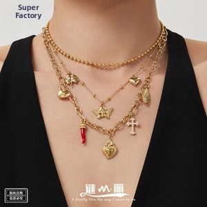 Close-up of triple-layered vintage gold necklace set with heart and cross charms