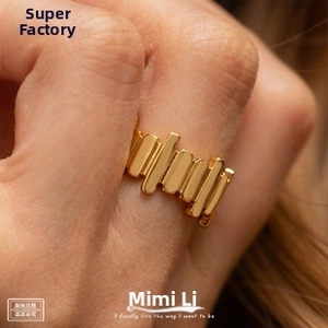 Macro shot of gold geometric chain style ring with vertical bar design on finger