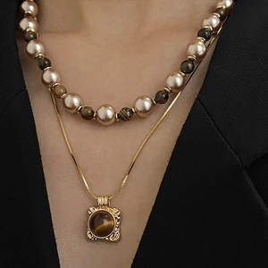 Détail d'un collier multicouche en œil de tigre et perles avec pendentif doré