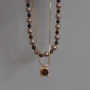 Détail du collier doré avec pendentif œil de tigre et chaîne de perles élégante