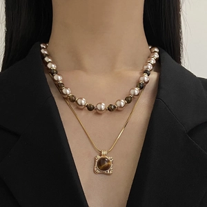 Gros plan du collier double rang en œil de tigre et perles sur blazer noir