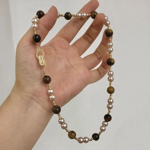 Détail du collier en œil de tigre et perles avec fermoir doré serti de zircon