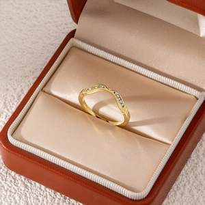 Detail of a wavy gold ring with micro-set zircons displayed in a luxury leather jewelry box