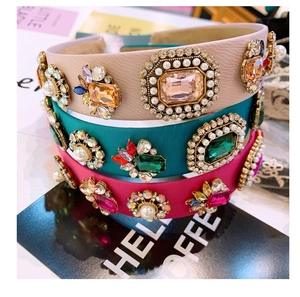 Close-up of three wide baroque headbands with colorful jewels and pearls on a magazine