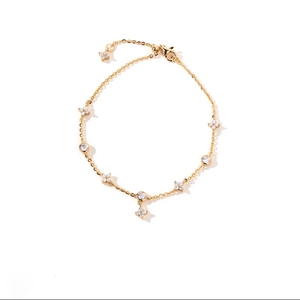 Macro detail of gold four-leaf clover bracelet with sparkling zircon and lobster clasp