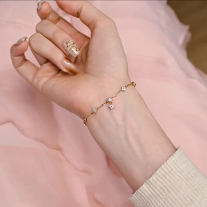 French style gold bracelet with tassel clover stars and sparkling zircon on woman's wrist