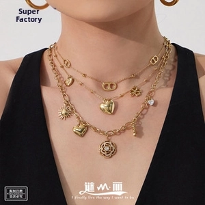 Detailed view of triple-layered gold necklaces with clover, heart, and flower charms