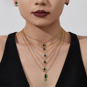Detail of layered gold necklaces with diverse green emerald-cut zircon pendants