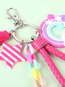 Rainbow keychain bag charm with pink tassel, star tag and braided cord on green surface