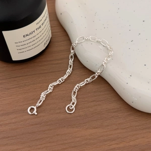 Macro detail of silver irregular link bracelet on white ceramic plate and wood background