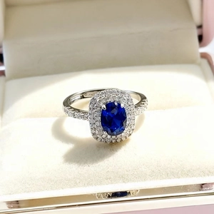 Macro view of oval royal blue sapphire ring with double halo diamond setting in white gold