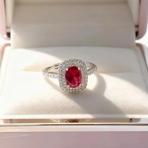 Macro shot of oval red ruby ring with double halo diamond setting in a jewelry box