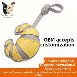 Detailed view of croissant-shaped leather keychain with yellow and grey grain texture