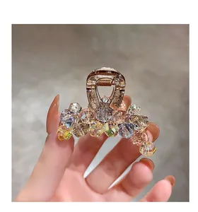 Close-up of golden metal hair claw with multi-colored crystal beads and luxury finish