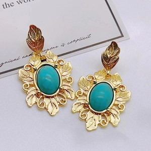 Vintage palace style turquoise earrings with golden leaf design on decorative background