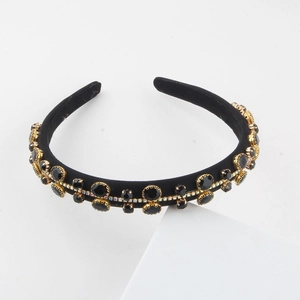 Close-up of black velvet headband featuring golden metal settings with gems and crystals