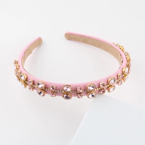 Detailed view of pink fabric headband with faux gemstones and gold metal settings