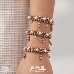 Detailed view of bohemian triple-layered beaded bracelet with gold pearls and tassel