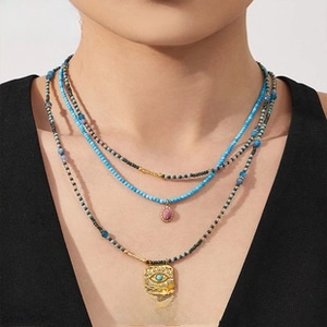 Layered beaded necklace set featuring pink gemstone and evil eye pendant detail