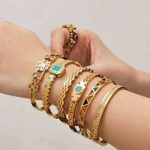 Detailed close-up of stacked gold-plated bracelets featuring enamel and zircon accents