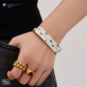 Detail of 18k gold plated hammered bangles with evil eye charms on a model's wrist