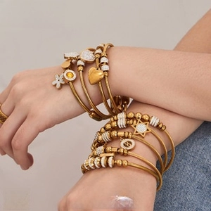 Close-up of gold layered wire bracelets with sparkling heart and star charms on wrist