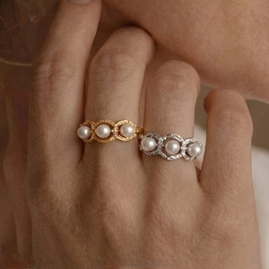 Close-up of elegant gold and silver rings with three pearls on a triple-band base