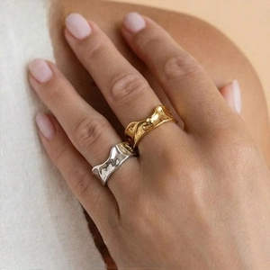 Detail of minimalist wave-textured rings in polished gold and silver on model hand