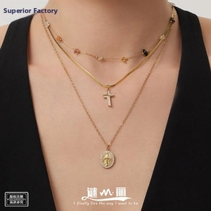 Macro detail of layered gold necklace with crucifix and saint medallion pendant set