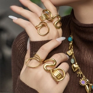 Detail of layered gold-plated stainless steel rings with textured wavy patterns