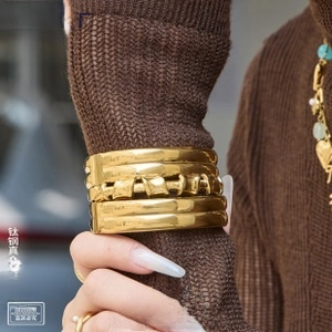 Detail of 18K gold-plated titanium steel twisted cuff bracelet with high-gloss finish