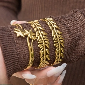 Close-up of gold-plated titanium steel bracelet set with star and leaf textures