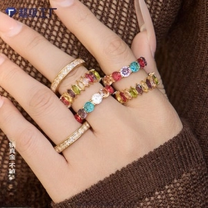 Close-up of stacked gold titanium rings with colorful zircon stones on woman's hand