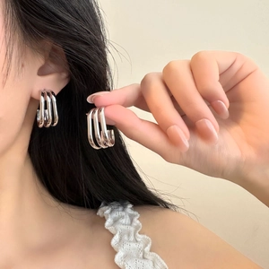 Detailed view of silver triple-layered titanium steel hoop earrings on model