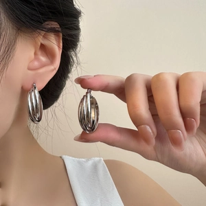 Detailed view of silver triple-hoop earrings in polished steel on a model