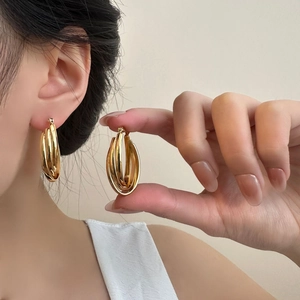 Macro detail of triple-layered gold polished hoop earrings showing luxury texture