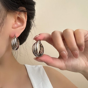 Detail shot of silver triple-layered interlaced hoop earrings in polished titanium steel