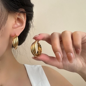 Detail of layered gold titanium steel hoop earrings shown on a model for a chic look