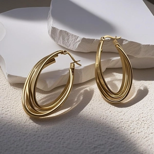 Close-up of golden multi-layer oval hoop earrings on a decorative white stone