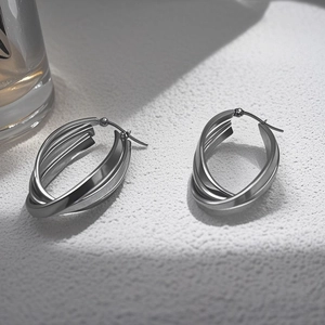 Detail of silver titanium steel earrings with a brushed triple-layer oval ring design