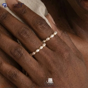 Close-up of minimalist pearl beaded rings on hand with gold bead accents