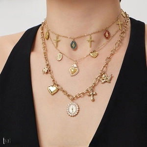 Close-up of layered gold titanium necklace featuring religious medals and cross charms