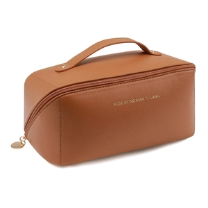 Detailed side view of brown leather makeup bag with gold zipper and embossed lettering