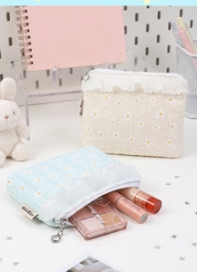Detail of daisy embroidery on pastel waffle fabric with lace trim and heart zipper pull