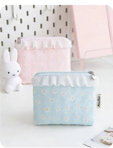 Detail of floral daisy makeup bags with lace trim and heart-shaped metal zipper pulls