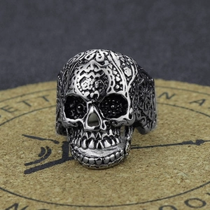 Detailed view of punk skull ring with red gemstone inlay on a rustic cork stand