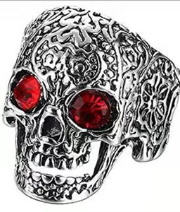 Macro detail of gothic skull ring with intricate silver texture and red gemstone eyes